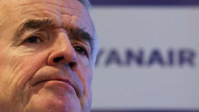 A close-up of frowning Ryanair CEO Michael O'Leary in front the company's logo.