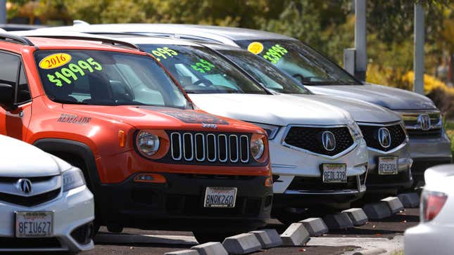 A photo of four different SUVs marked up for sale in a car garage. 