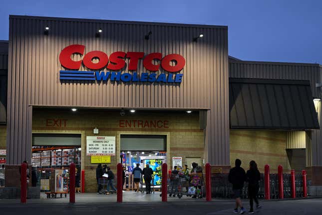 Exterior of a Costco store at dusk with shoppers entering