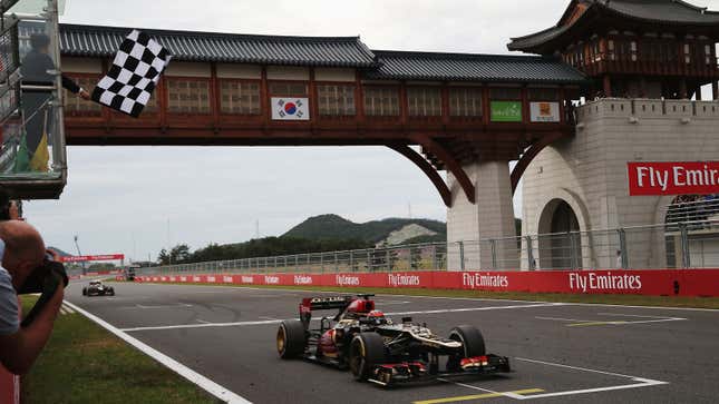 A photo of a black and gold Lotus car crossing the finish line in Korea. 