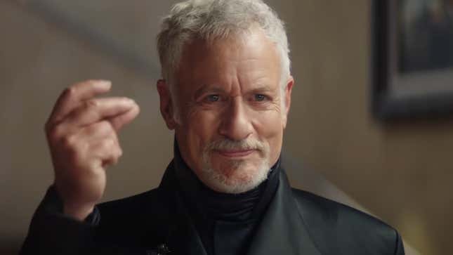 Q (John De Lancie) snaps his fingers in a display of his omnipotent power.