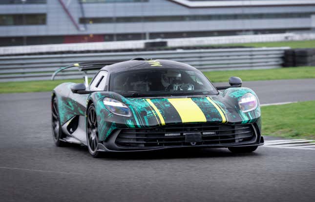 Front 3/4 view of a camouflaged Aston Martin Valhalla driving on track