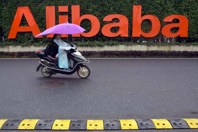 FILE - A woman rides a scooter past the company logo outside the Alibaba Group headquarters in Hangzhou, in eastern China&#39;s Zhejiang province, May 27, 2016. Shares of Chinese e-commerce firm Alibaba Group Holding plunged as much as 10% in New York after it said Thursday, Nov. 16, 2023, that plans to spin off its cloud business were scrapped, citing uncertainties due to U.S. chip restrictions. (AP Photo/Ng Han Guan, File)