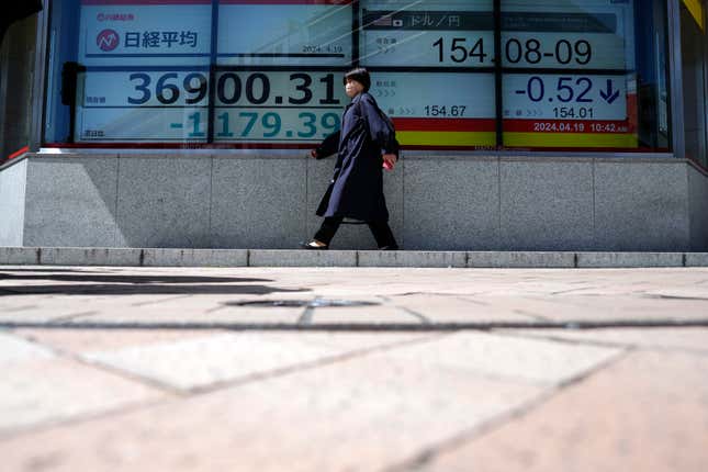 A person walks in front of an electronic stock board showing Japan&#39;s Nikkei 225 index at a securities firm Friday, April 19, 2024, in Tokyo. (AP Photo/Eugene Hoshiko)