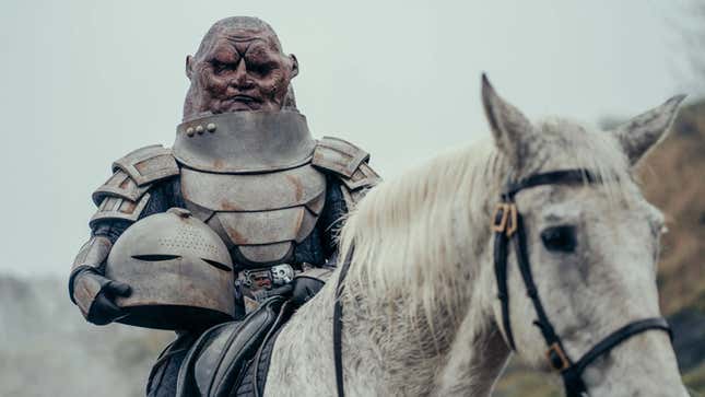 A Doctor Who Sontaran, helmet under one arm, rides atop a white horse.