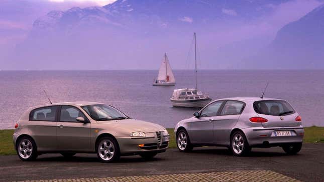 Two Alfa Romeo hatchbacks parked by a lake 