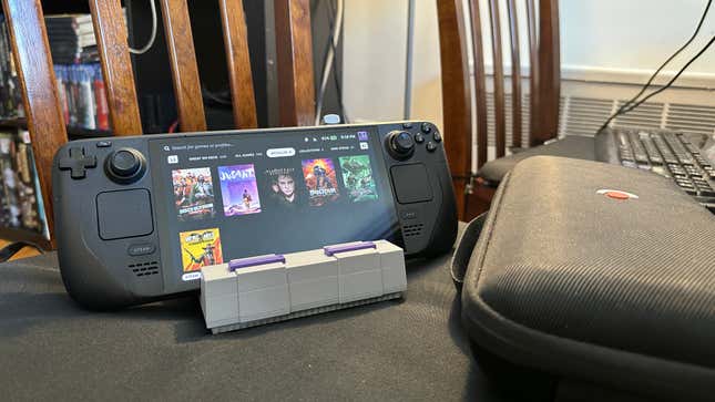 A Steam Deck OLED on top of a custom dock next to a Steam Deck case and controller