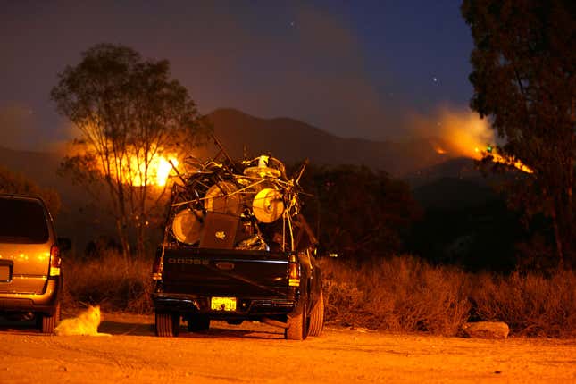 Evacuees pass the night in a truck filled with possessions near Interstate 15 and Pala Road watching distant flames as the Rice Fire destroys at least 100 homes on October 22, 2007 near Fallbrook, California