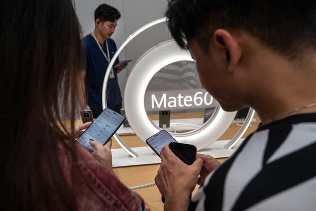 People looking at Mate 60 smartphones with a Mate 60 sign in the background