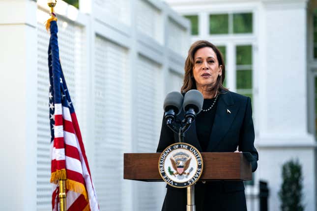 Kamala Harris, vêtue d’un look entièrement noir, se tient sur un podium à côté d’un drapeau américain