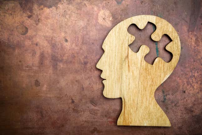 A wooden portrait of a person’s head, with a missing puzzle piece.