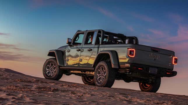 A Jeep Gladiator parked on sand with its roof down 