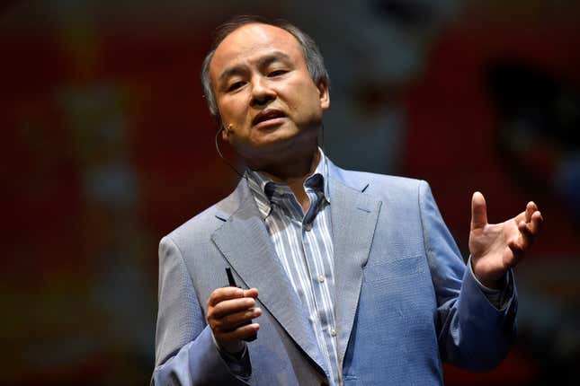 Masayoshi Son speaking while wearing a grey suit jacket and grey striped button down