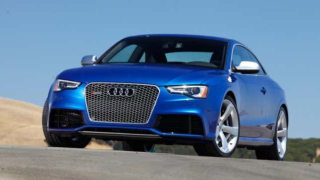 A blue Audi RS5 parked on a race track showing its beautiful mesh grille, satin wing mirror covers, and oversized alloy wheels