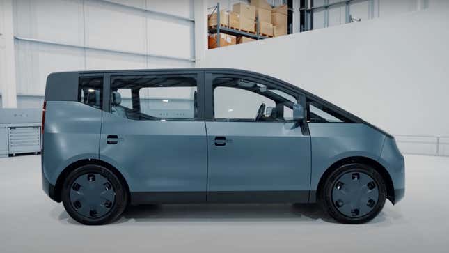 A grey electric vehicle with a boxy rear and long, curved front end. 