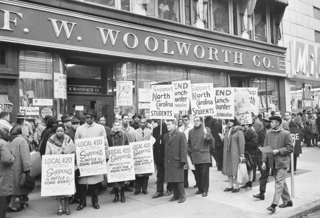 Manifestantes con carteles protestan frente a una tienda FW Woolworth en Harlem para oponerse a la contradiscriminación en el almuerzo practicada en las tiendas Woolworth en Greensboro, Charlotte y Durham, Carolina del Norte. Los manifestantes, que pertenecen a una organización conocida como “CORE” (Congreso de Igualdad Racial), Los residentes de Harlem no frecuentarán las tiendas Woolworth hasta que termine la discriminación en las tiendas de las tres ciudades del sur.