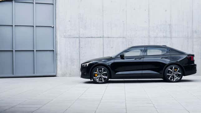 A photo of a black Polestar 2 sedan parked by a garage door. 