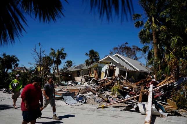 FILE - Men walk past destroyed homes and debris as they survey damage to other properties, two days after the passage of Hurricane Ian, in Fort Myers Beach, Fla., on Sept. 30, 2022. Florida insurance companies made money last year for the first time in seven years, thanks to investment income and a mild hurricane season, according to an analysis conducted by S&amp;P Global Market Intelligence. A group of around 50 insurers reported $147.3 million in net income for 2023, compared to net losses of more than $1 billion in each of the previous two years, according to the analysis released last week. (AP Photo/Rebecca Blackwell, File)