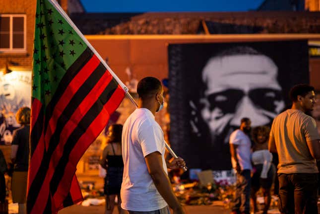 A man carries a Black Liberation flag through a Juneteenth celebration at the memorial for George Floyd outside Cup Foods on June 19, 2020, in Minneapolis, Minnesota.