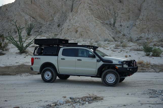 A beige Ford Ranger set up for off-roading in a desert canyon