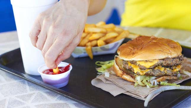 Un client mangeant un hamburger et des frites de restauration rapide