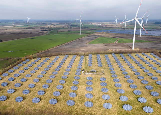 Solar panels stand on the edge of a wind farm in Sprakebuell, Germany, Thursday, March 14, 2024. Sprakebuell is something of a model village for the energy transition - with an above-average number of electric cars, a community wind farm and renewable heat from biogas. All houses in the village center have been connected to the local heating network and all old oil heating systems have been removed. Aerial photography with a drone. (AP Photo/Frank Molter) (AP Photo/Frank Molter)