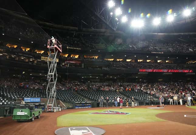 Beekeeper Matt Hilton removes a bee swarm on the home plate net delaying the start of the game between the Dodgers and the Diamondbacks at Chase Field in Phoenix on April 30, 2024.