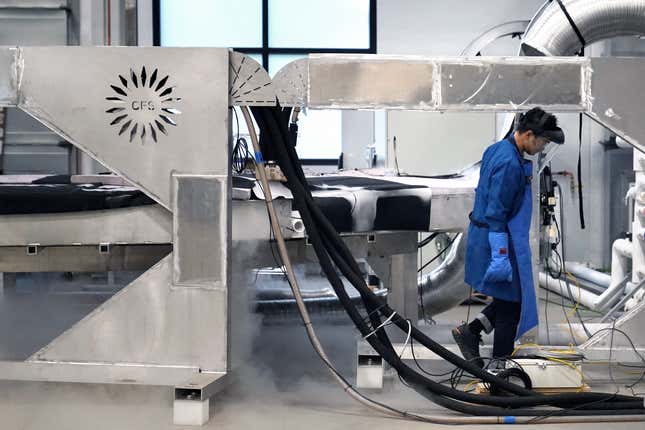 Ingeniero con equipo de protección azul caminando entre estructuras metálicas