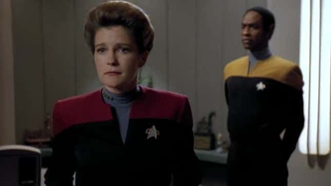 Captain Janeway sadly looks away from Tuvok, as he stands at attention in her office.