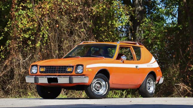 une AMC Gremlin orange vif garée devant des arbres