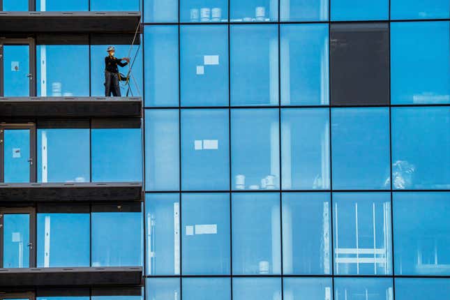 A construction worker checks his safety gear while working on a balcony on a high-rise residential building under construction in Arlington, VA., Monday, Oct. 16, 2023. On Tuesday, the government is releasing its latest quarterly report on wages and salaries. In the previous report, those labor costs grew more slowly, suggesting that employers were feeling less pressure to boost pay. (AP Photo/J. David Ake)