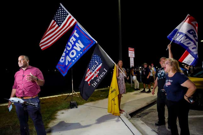 Supporters of former President Donald Trump shout as Kamrel Eppinger reports live for WPTV News Channel 5 near the home of former President Donald Trump at Mar-A-Lago on August 8, 2022, in Palm Beach, Florida.