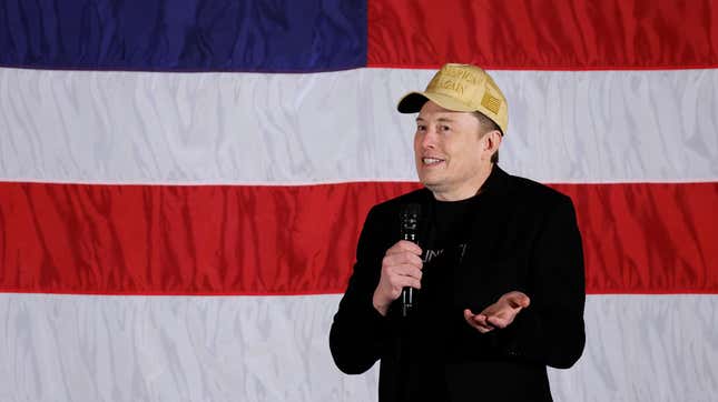 A photo of Elon Musk wearing a Donald Trump hat. 