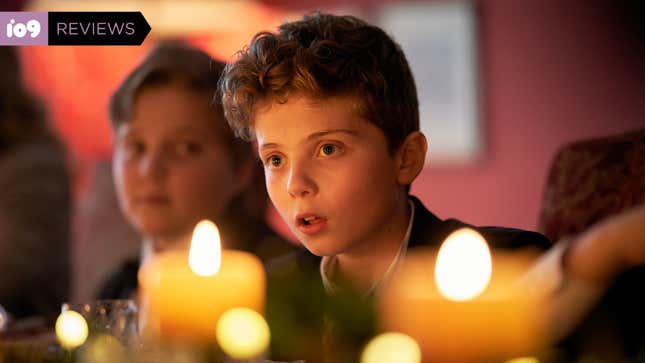 A small boy looks aghast while sitting at a festive dinner table decorated with candles.