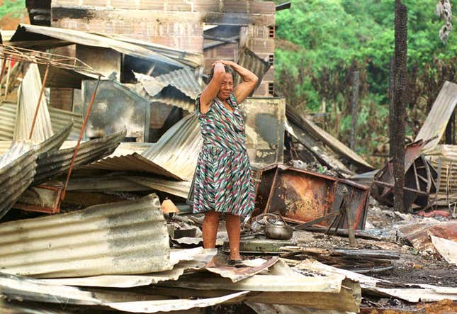 A woman stands in the wreckage of her house, which was destroyed during a FARC attack.