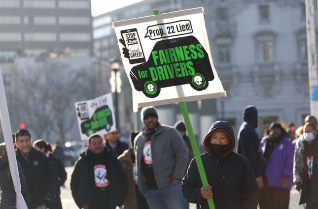 A protestor stands outside with a sign reading "Prop 22 lied! Fairness for drivers." More protesters are visible in the background.