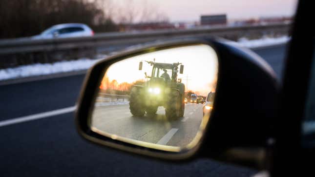 Una foto de un tractor que aparece en el espejo de un automóvil. 