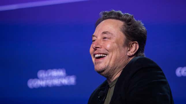 A photo of Elon Musk smiling on stage. 