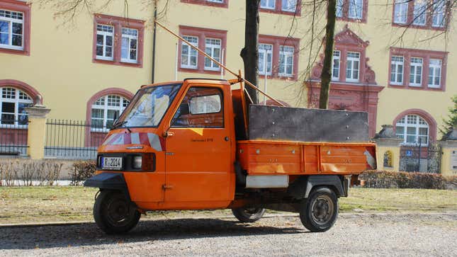 A photo of an orange VespaCar truck. 