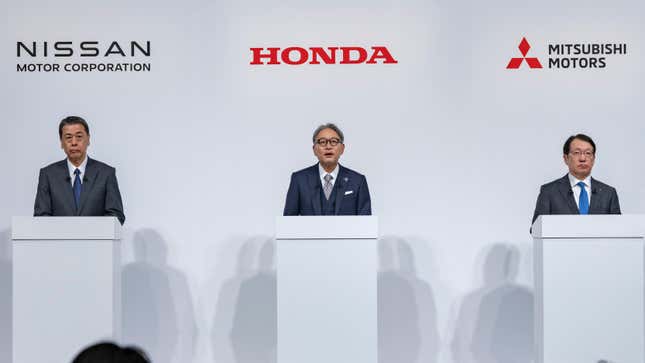 a photo of CEOs from nissan honda and Mitsubishi standing behind podiums discussing a merger