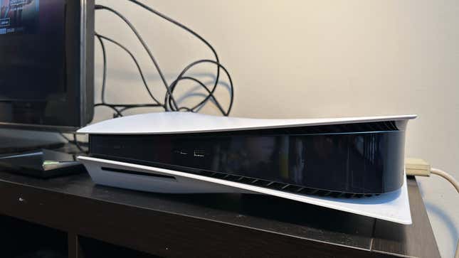 A PlayStation 5 console on a TV stand next to a TV