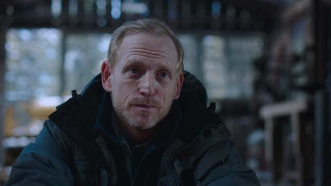 David is seen sitting in a wood shed and talking to someone off-screen.