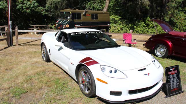 a white c6 corvette parked on grass with a plaque