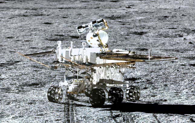 A six-wheeled rover (Yutu-2) sits centrally on the grey background of the lunar surface.