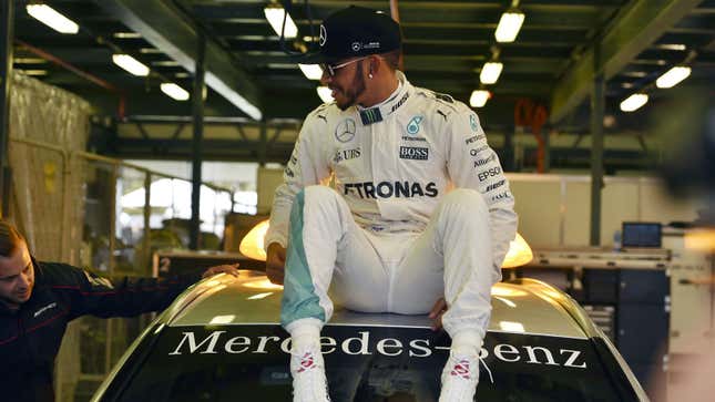 A photo of Lewis Hamilton on the roof of a car. 