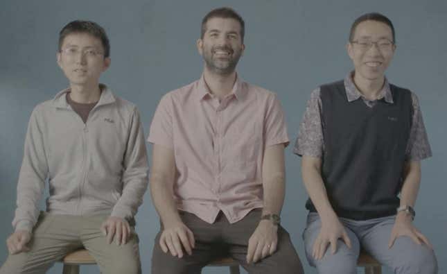 three men sitting on stools side by side, their hands are resting on their legs