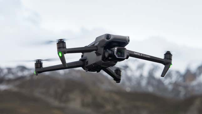 The DJI Mavic 3 Classic drone pictured flying with mountains in the background.