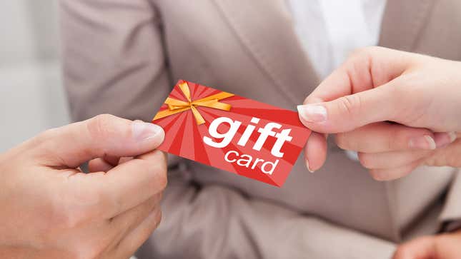 An image shows someone giving a person a gift card. 