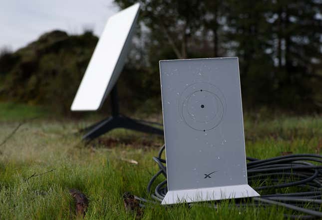 business new tamfitronics Starlink dish and router, two white rectangular boxes, in a grassy field