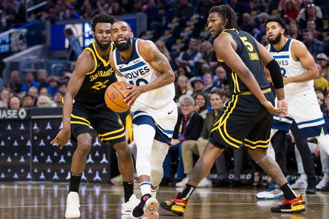 Nov 14, 2023; San Francisco, California, USA; Minnesota Timberwolves guard Mike Conley (10) prepares to shoot in front of Golden State Warriors forward Kevon Looney (5) and forward Andrew Wiggins (22) during the first half at Chase Center.